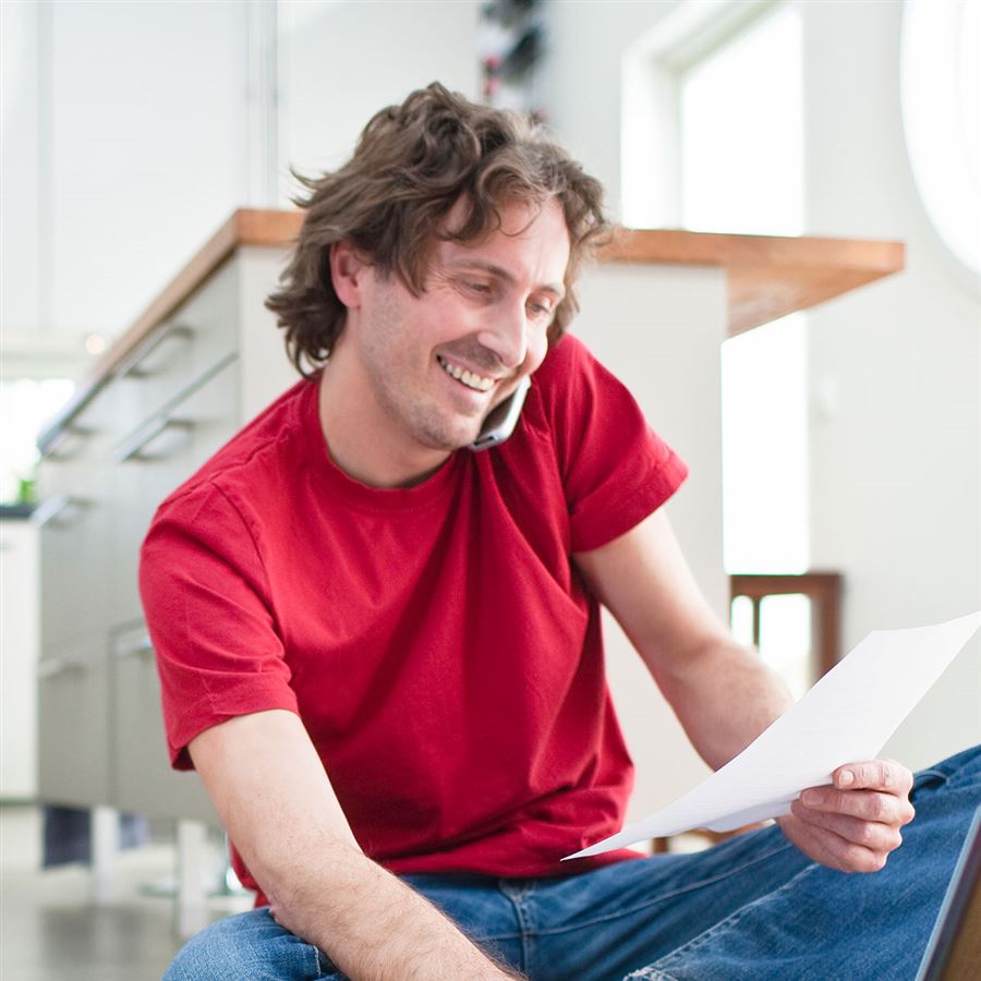 man aan de telefoon met een papier in zijn hand