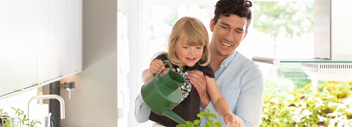 Vader en zoon geven de plantjes water in de keuken