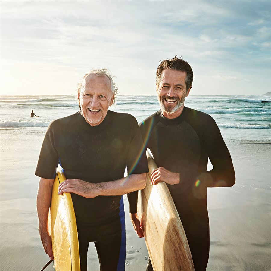 Vader en zoon komen uit de zee met hun surfplank